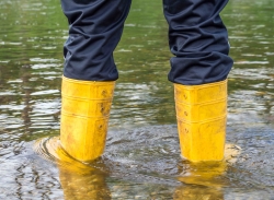 Person wearing boots in the floodwaters